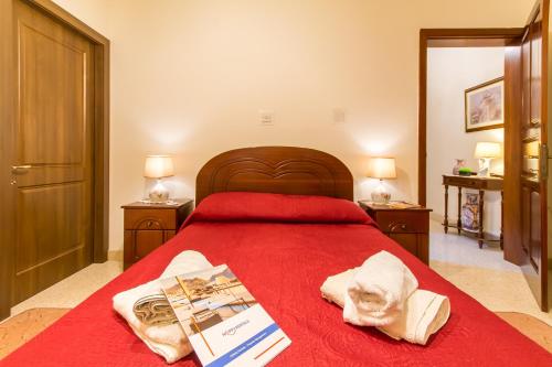 a bedroom with a red bed with a book and towels at Sunny Maltese townhouse Madonnina Kalkara - Happy Rentals in Kalkara