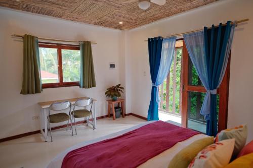 a bedroom with a bed and a desk and windows at Copacabana Siargao in General Luna