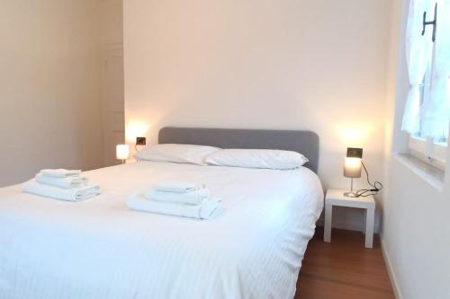una camera da letto con un letto bianco e asciugamani di Vicino Zoncolan+Netflix e Wifi a Treppo Carnico