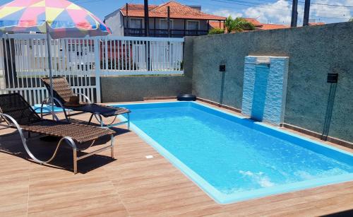 una piscina con dos sillas y una sombrilla en Mar Doce Lar, en Guaratuba