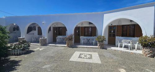 un edificio blanco con sillas y mesas en un patio en Hotel Palladion, en Karterados