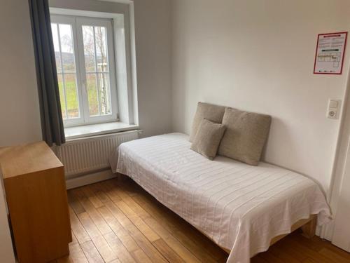a small bed in a room with a window at Die Strumpffabrik - Guesthouse in Kerpen