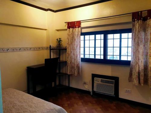 1 dormitorio con cama, ventana y escritorio en Greenhills Garden Square, en Manila