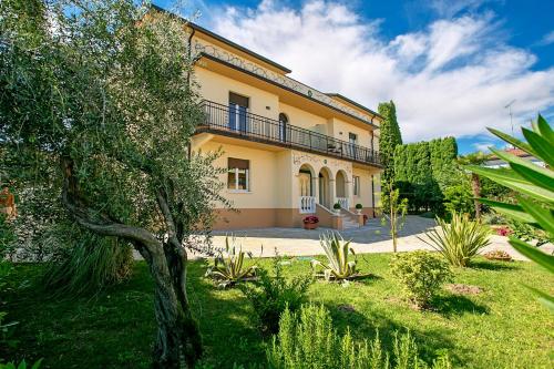 uma grande casa amarela com uma árvore no quintal em Villa Mimosa - Appartamento 2 - Happy Rentals em Desenzano del Garda