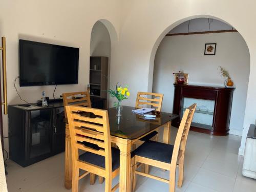 Un comedor con una mesa con sillas y un televisor. en 2bhk with Swimming pool & Kitchen, en Candolim