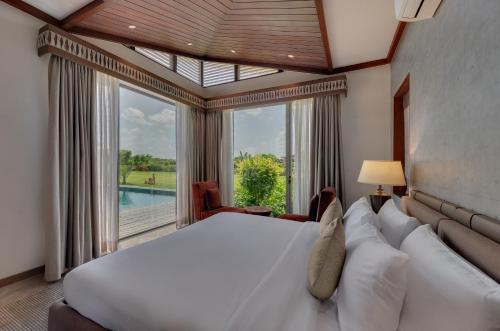 a bedroom with a large bed and a large window at The Fern Royal Farm Resort, Anjar in Anjār