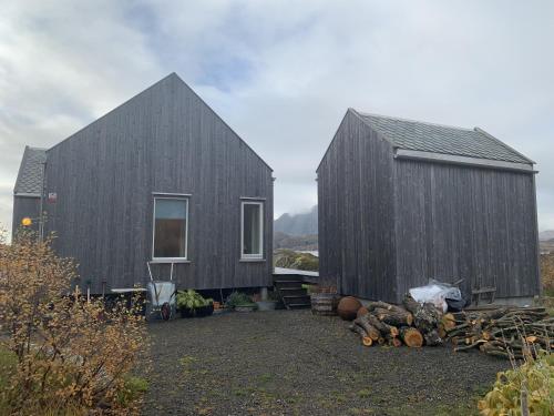a couple of black houses with a pile of logs at Unique private cabin in Lofoten in Leknes