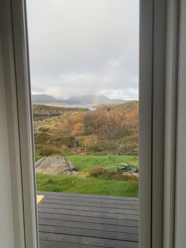 an open door with a view of a field and water at Unique private cabin in Lofoten in Leknes