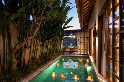 a pool in the middle of a house with candles in it at Asvara Villa Ubud by Ini Vie Hospitality in Ubud