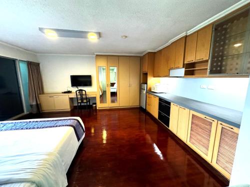 a bedroom with a bed and a kitchen with cabinets at The Step Sathon in Bangkok