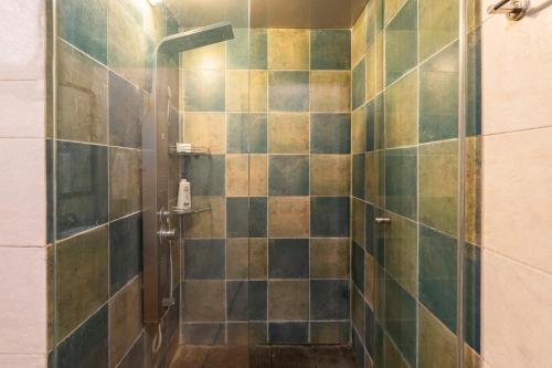 ein Bad mit einer Dusche mit grünen und braunen Fliesen in der Unterkunft Vintage Estate - Lakeside allure with vintage decor,A plunge pool & A lawn featuring a charming gazebo in Karjat