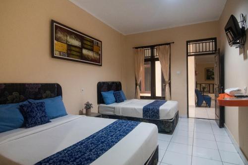 a hotel room with two beds and a balcony at Miraa Guest House & Resto in Denpasar