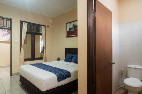een slaapkamer met een bed en een toilet bij Miraa Guest House & Resto in Denpasar