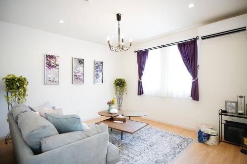 a living room with a couch and a table at 【5名様まで宿泊費用変動なし！】落ち着いた雰囲気を味わえる白を基調としたモダンスタイルな貸切一軒家！ in Meta