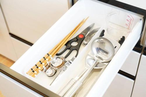 a white tray with scissors and other kitchen utensils at 【5名様まで宿泊費用変動なし！】落ち着いた雰囲気を味わえる白を基調としたモダンスタイルな貸切一軒家！ in Meta
