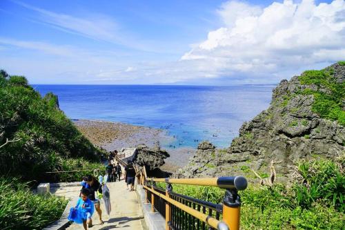 a group of people walking down a path near the ocean at 【5名様まで宿泊費用変動なし！】落ち着いた雰囲気を味わえる白を基調としたモダンスタイルな貸切一軒家！ in Meta