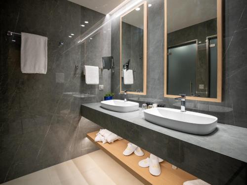 ein Badezimmer mit zwei Waschbecken und einer Dusche in der Unterkunft Ammoa Luxury Hotel & Spa Resort in Nikiti