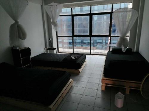 チェンマイにあるLita Guesthouseの大きな窓付きの客室で、ベッド3台が備わります。
