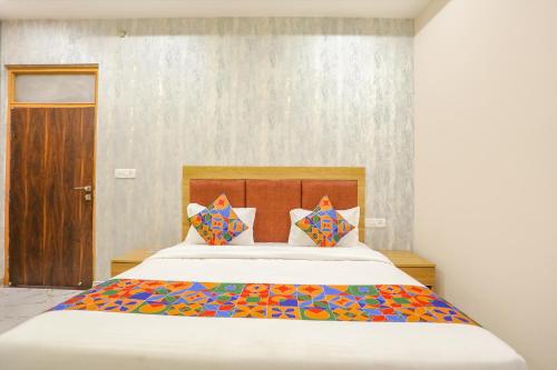 een slaapkamer met een groot bed met kleurrijke kussens bij FabHotel Maharishi inn in Ayodhya