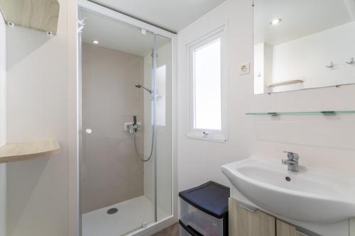 une salle de bain blanche avec un lavabo et une douche dans l'établissement Mobil Home 3ch Acces Direct Plage, à Canet