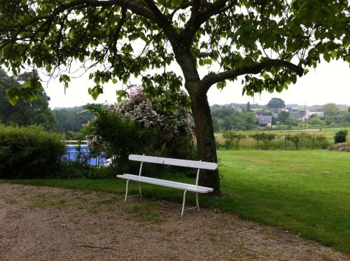 a white park bench sitting next to a tree at La Butte de Gohier in Blaison