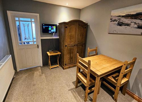 a dining room with a wooden table and a television at The Pit Stop Cafe and Accomodation in Cymmer