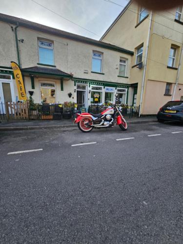 a red motorcycle parked on the side of a street at The Pit Stop Cafe and Accomodation in Cymmer