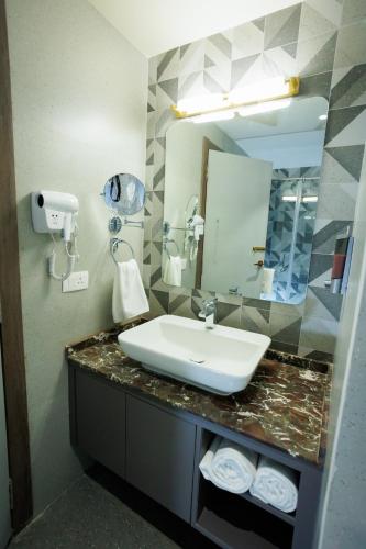 a bathroom with a sink and a mirror at AJ GRAND ELITE HOTEL in Mangalore