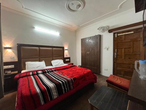 a bedroom with a large bed with a red blanket at Hotel Premier Mall Road Manali in Manāli