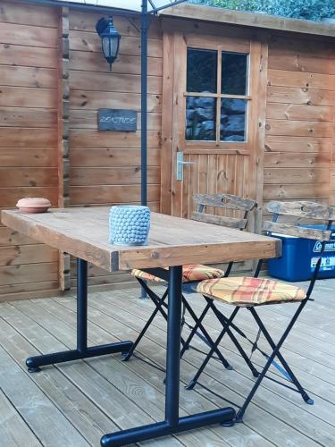 a picnic table and a chair on a deck at Chalet Zenitude in Breil-sur-Roya