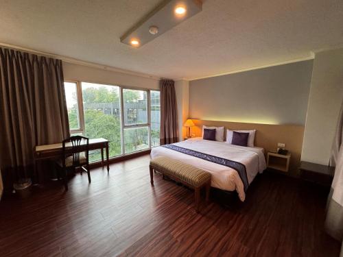 a hotel room with a bed and a desk and window at Collection O The Step Sathorn in Bangkok