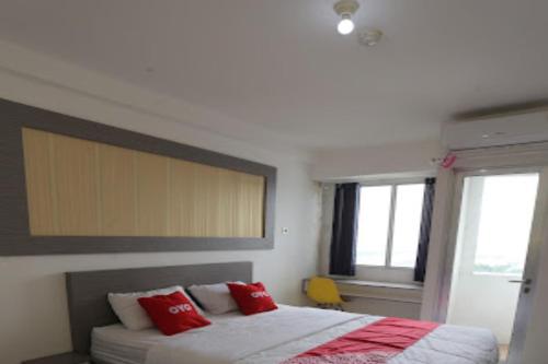 a bedroom with a large bed with red pillows at Capital O 93730 Alima View Syariah in Bekasi