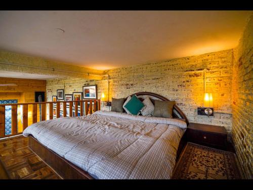 a bedroom with a bed and a brick wall at SaffronStays Ekam Walnut Suite, Chail in Kandāghāt