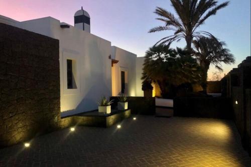 a house with a courtyard with a palm tree and lights at Beautiful holiday home in Playa Blanca with pool in Playa Blanca