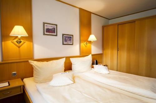 a bedroom with a large white bed with two pillows at Villa Valluga in Mittelberg