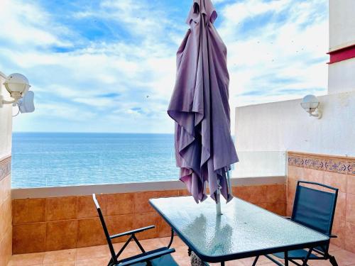 a table with an umbrella on a balcony with the ocean at Seafront apartment in La Garrofa near the beach in La Garrofa