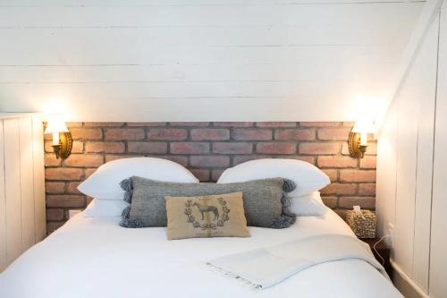 1 dormitorio con cama blanca y pared de ladrillo en Anavo Farm’s Chic Sheep Retreat, en Solvang