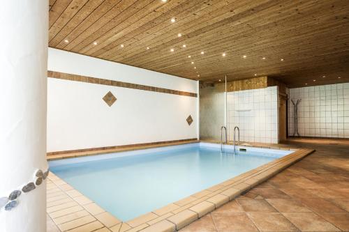 a swimming pool in a building with a wooden ceiling at Villa Valluga in Mittelberg
