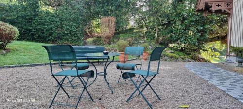 three chairs and a table in front of a bench at Le Manoir Au Lac in Gérardmer
