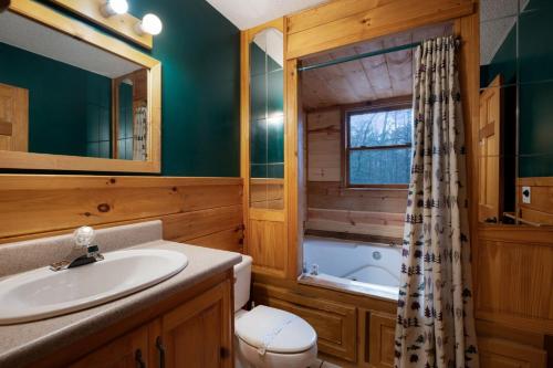 a bathroom with a sink and a toilet and a tub at Peaceful Living Minutes from Blue Ridge hot tub pool table in Blue Ridge