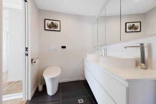 a white bathroom with two sinks and a toilet at Pinnacles on Victoria St in Wellington