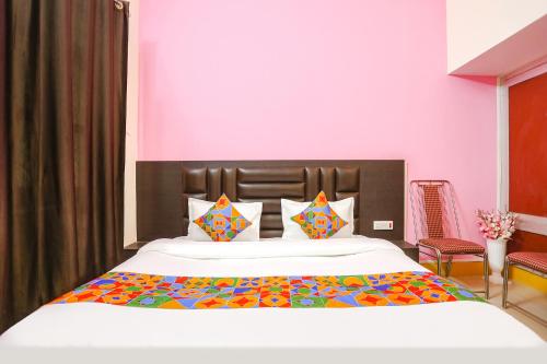 1 dormitorio con 1 cama blanca grande con almohadas coloridas en FabHotel Madhuri Annex, en Ayodhya