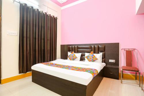 1 dormitorio con 1 cama grande y paredes de color rosa en FabHotel Madhuri Annex, en Ayodhya