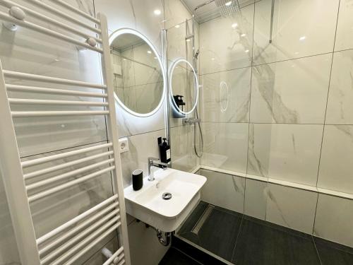 een witte badkamer met een wastafel en een spiegel bij City Spot Zimmer24Frei in Köln in Keulen