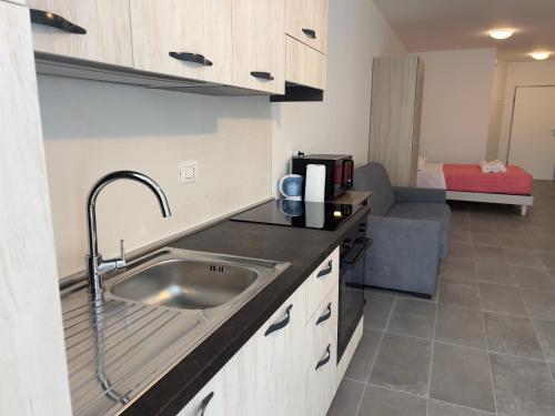 a kitchen with a sink and a couch in a room at Quintarelli Home Europa 2 in Negrar
