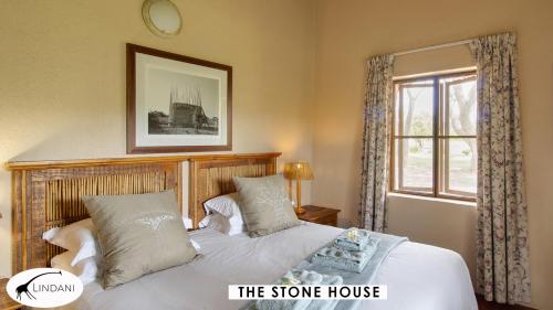 a bedroom with a bed with a wooden headboard and a window at Lindani Game and Lodges in Vaalwater