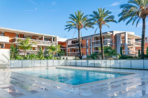 - une piscine bordée de palmiers et de bâtiments dans l'établissement Royal Cap, à Villeneuve-Loubet