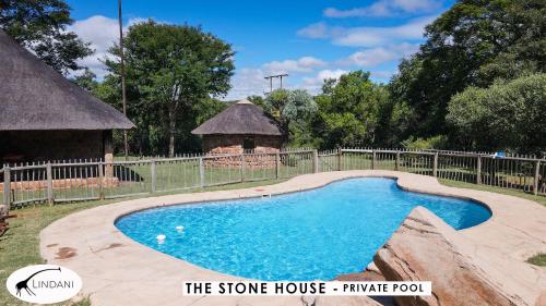 a pool in a yard with a fence and a house at Lindani Game and Lodges in Vaalwater