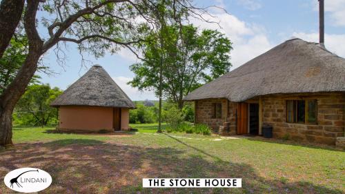 a stone house and a stone house with a tree at Lindani Game and Lodges in Vaalwater