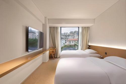 a hotel room with three beds and a window at Yolo Vacation Homestay in Sanya